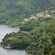 A series of tile roofed buildings terrraced into a verdant mountain landsape next to the water